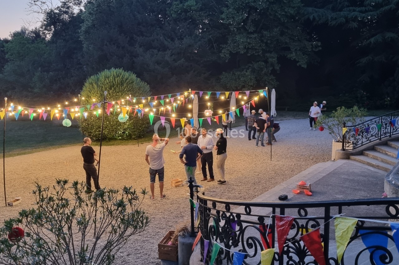 Personnes discutant dans une cour décorée de guirlandes lumineuses et de fanions colorés, en soirée en plein air.