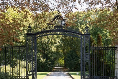 Façade d'un château illuminé la nuit avec une fontaine ornée de statues au premier plan.