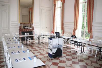 Façade d'un château illuminé la nuit avec une fontaine ornée de statues au premier plan.
