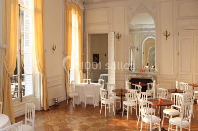 Façade d'un château illuminé la nuit avec une fontaine ornée de statues au premier plan.