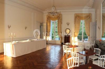Façade d'un château illuminé la nuit avec une fontaine ornée de statues au premier plan.
