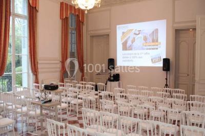 Façade d'un château illuminé la nuit avec une fontaine ornée de statues au premier plan.