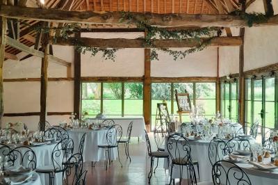 Voiture ancienne rouge décorée de fleurs blanches et feuillages, stationnée devant un bâtiment à colombages.