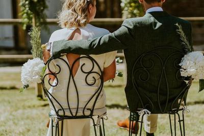Voiture ancienne rouge décorée de fleurs blanches et feuillages, stationnée devant un bâtiment à colombages.