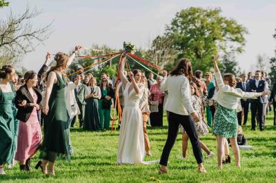 Voiture ancienne rouge décorée de fleurs blanches et feuillages, stationnée devant un bâtiment à colombages.