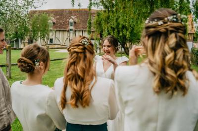 Voiture ancienne rouge décorée de fleurs blanches et feuillages, stationnée devant un bâtiment à colombages.