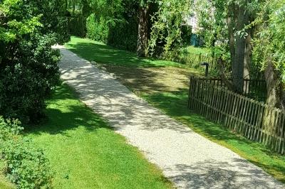 Voiture ancienne rouge décorée de fleurs blanches et feuillages, stationnée devant un bâtiment à colombages.
