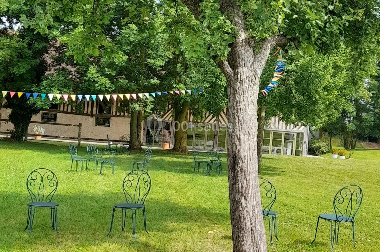 Chaises en métal et bottes de paille disposées sur une pelouse avec des arbres et des fanions colorés en arrière-plan.