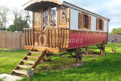 Voiture ancienne rouge décorée de fleurs blanches et feuillages, stationnée devant un bâtiment à colombages.