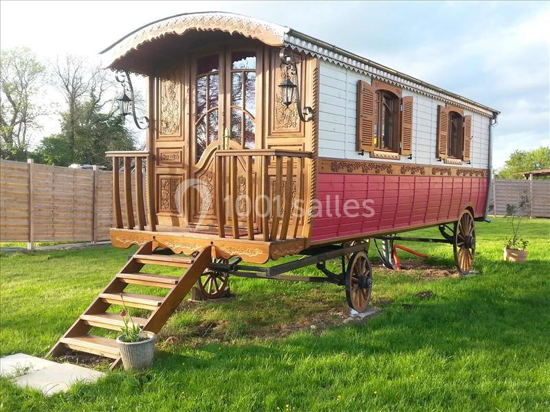 Roulotte en bois décorée, installée sur une pelouse, avec des escaliers menant à l'entrée.