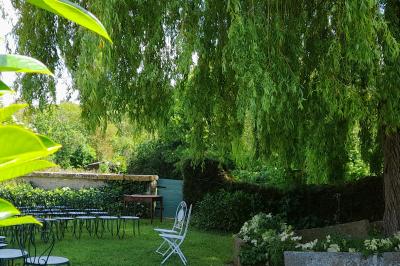 Voiture ancienne rouge décorée de fleurs blanches et feuillages, stationnée devant un bâtiment à colombages.