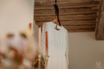 Voiture ancienne rouge décorée de fleurs blanches et feuillages, stationnée devant un bâtiment à colombages.