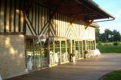 Voiture ancienne rouge décorée de fleurs blanches et feuillages, stationnée devant un bâtiment à colombages.