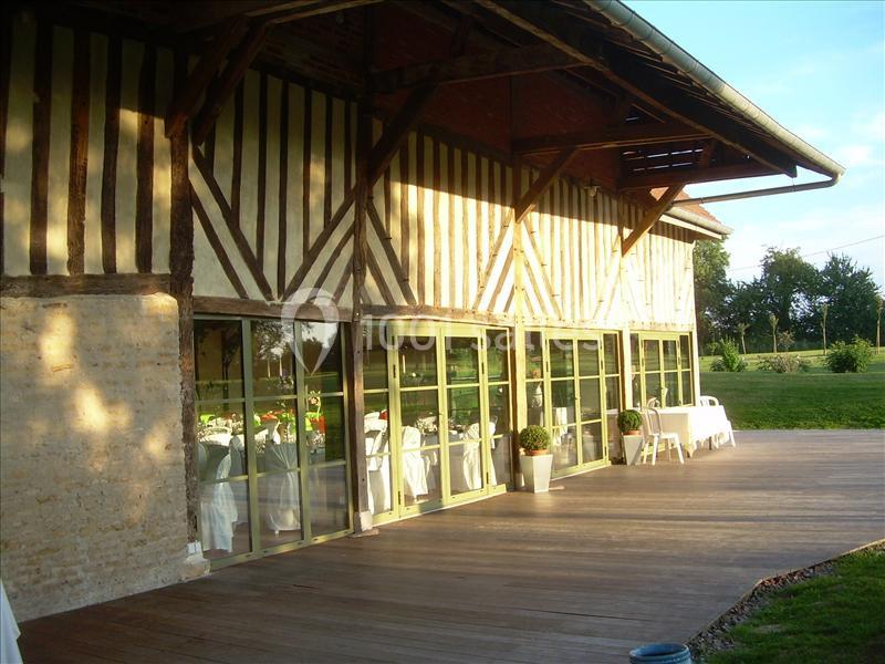 Bâtiment à colombages avec une terrasse en bois, grandes baies vitrées et vue sur un espace vert.