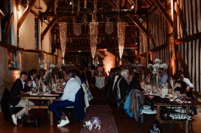 Voiture ancienne rouge décorée de fleurs blanches et feuillages, stationnée devant un bâtiment à colombages.