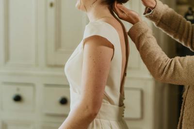 Voiture ancienne rouge décorée de fleurs blanches et feuillages, stationnée devant un bâtiment à colombages.
