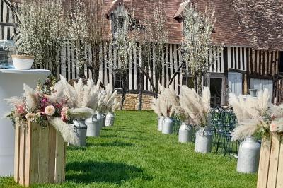 Voiture ancienne rouge décorée de fleurs blanches et feuillages, stationnée devant un bâtiment à colombages.