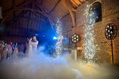 Salle en briques avec un plafond en bois, éclairages festifs, fumée au sol et gerbes d'étincelles allumées.