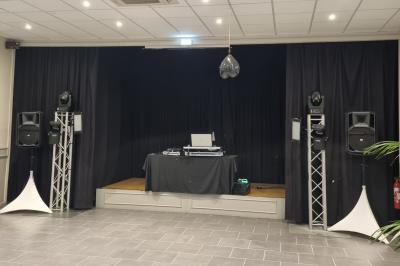 Des personnes dansent et chantent dans une salle éclairée de lumières colorées, avec un chanteur au premier plan.