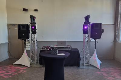 Des personnes dansent et chantent dans une salle éclairée de lumières colorées, avec un chanteur au premier plan.