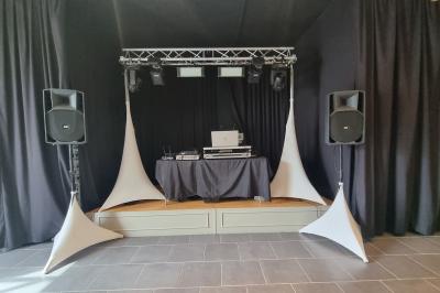 Deux DJ mixent sur une scène éclairée par des projecteurs colorés, devant un écran affichant ’Don't Care Project’.