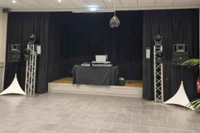 Deux DJ mixent sur une scène éclairée par des projecteurs colorés, devant un écran affichant ’Don't Care Project’.