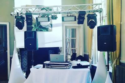 Deux DJ mixent sur une scène éclairée par des projecteurs colorés, devant un écran affichant ’Don't Care Project’.