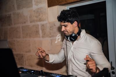 Un DJ concentré mixe de la musique sur une console dans une pièce aux murs en pierre.