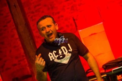 Un DJ mixant sur des platines dans une salle éclairée par des lumières rouges.