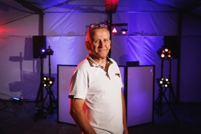 Homme debout dans une tente éclairée par des projecteurs colorés, entouré d'équipements d'éclairage.