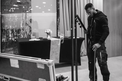 Un technicien ajuste un support d'éclairage dans une salle équipée de matériel et décorée de rideaux.