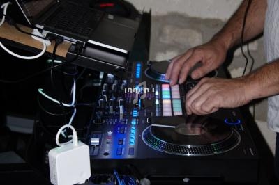Un DJ utilise une table de mixage équipée de boutons lumineux et d'un ordinateur portable.