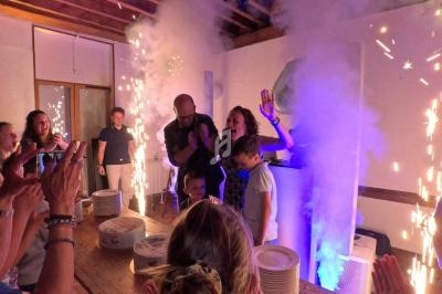Des personnes célèbrent un événement dans une pièce illuminée par des étincelles et des effets de fumée.