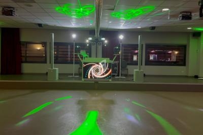 Salle de réception avec piste de danse éclairée par des lumières vertes et une table de DJ équipée d'un écran animé.