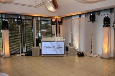 Installation de matériel de sonorisation et d'éclairage dans une salle avec une table de DJ et un écran personnalisé.