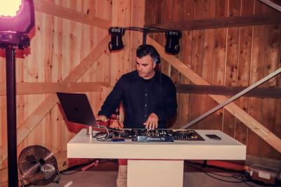 Personnes dansant sous des lumières colorées dans une salle sombre avec une scène équipée de matériel de DJ.