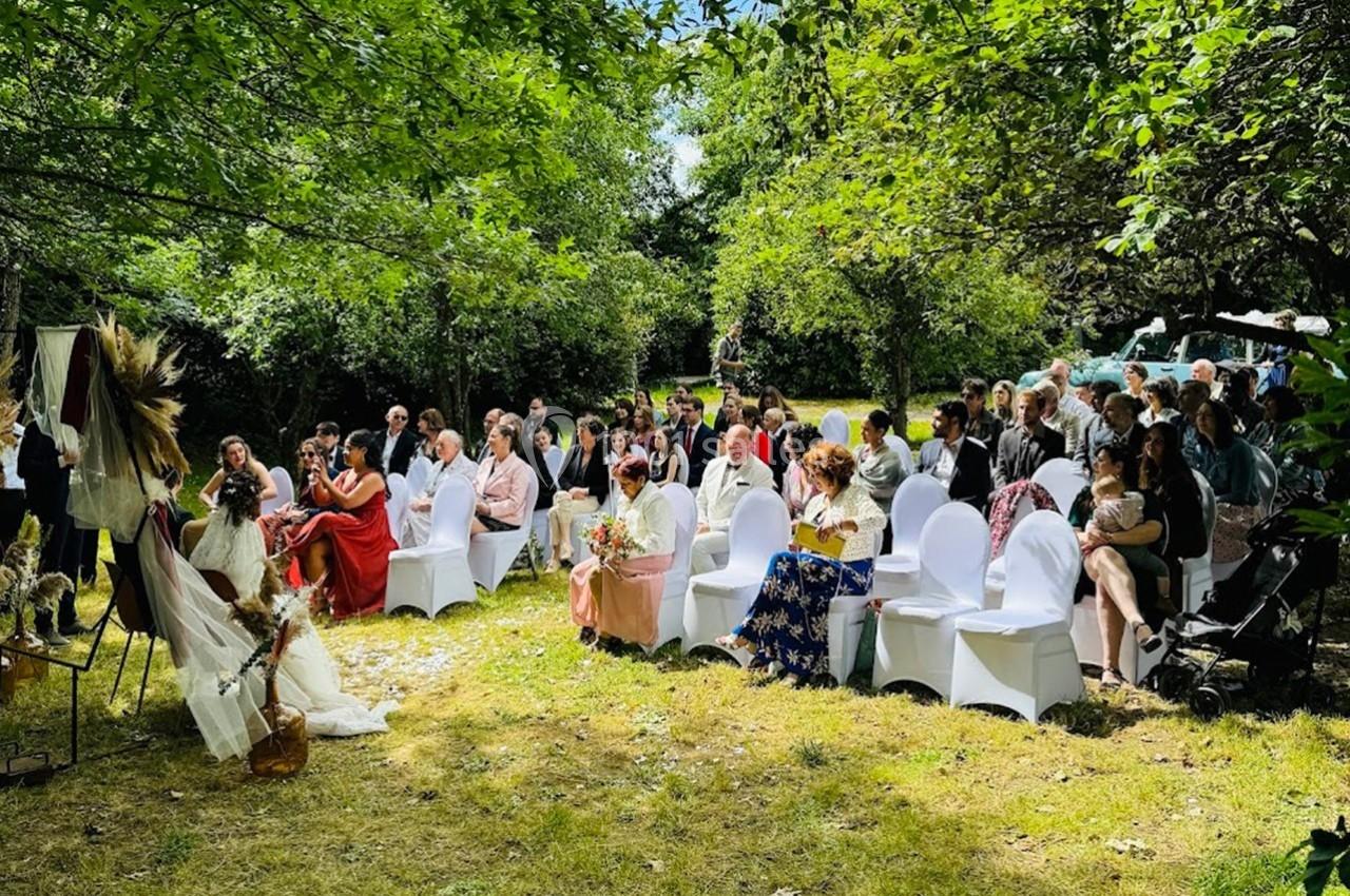 Un groupe de personnes assises en plein air lors d'une cérémonie dans un jardin verdoyant.