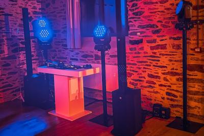 Personnes dansant sous des lumières colorées dans une salle sombre avec une scène équipée de matériel de DJ.