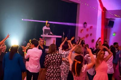 Personnes dansant sous des lumières colorées dans une salle sombre avec une scène équipée de matériel de DJ.