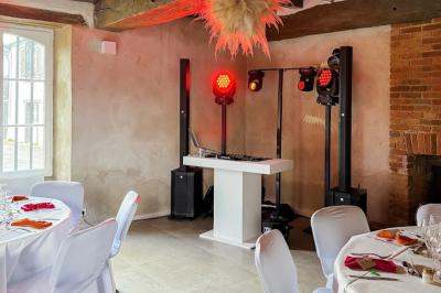 Personnes dansant sous des lumières colorées dans une salle sombre avec une scène équipée de matériel de DJ.