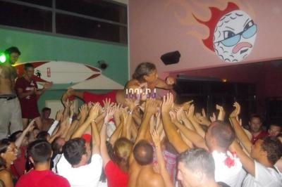 Un chanteur porté par la foule dans une ambiance festive, avec une décoration murale colorée en arrière-plan.