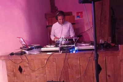 Un DJ mixe de la musique sur une table de mixage dans un espace intérieur avec un éclairage rose.