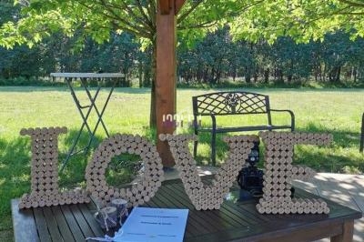 Décoration en liège formant le mot ’LOVE’ sur une table en bois sous une pergola, dans un jardin ensoleillé.