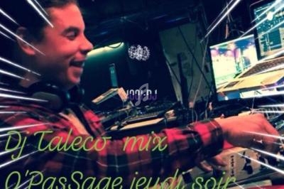 Un DJ souriant mixe de la musique sur une table de mixage dans un environnement sombre et animé.