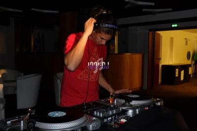 Un DJ mixant sur des platines vinyles dans une pièce faiblement éclairée.