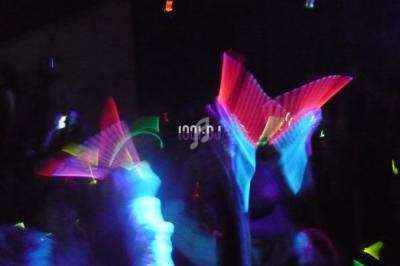 Personnes dans une ambiance festive avec des lumières fluorescentes et des accessoires lumineux colorés.