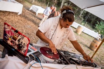 Un DJ mixe de la musique sur des platines vinyles lors d'un événement en extérieur sous une tente.