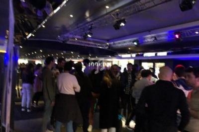 Des personnes rassemblées dans un espace intérieur éclairé, avec des lumières colorées et une ambiance animée.