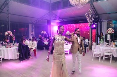 Un couple danse au centre d'une salle de réception décorée avec des fleurs et éclairée par des lumières colorées.