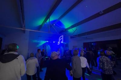 Des personnes dansent dans une salle éclairée par des lumières colorées et des projecteurs.